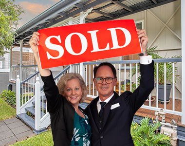 Grant and Christina Penrose holding up a SOLD sign together