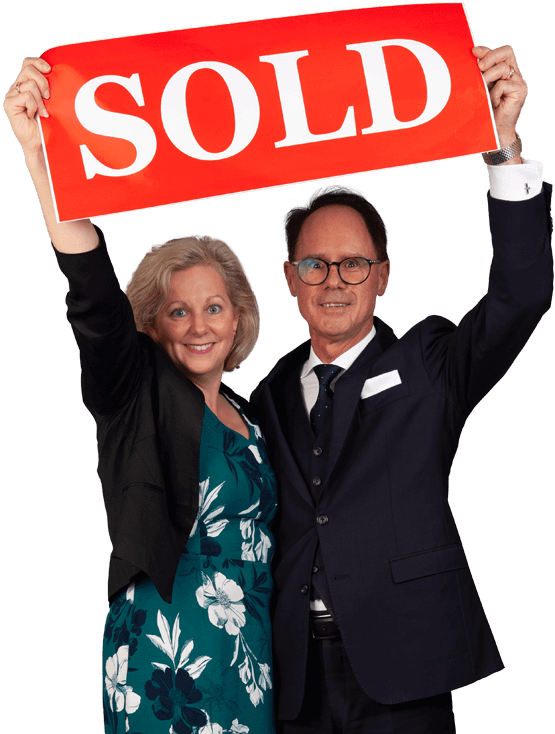 Christina and Grant Penrose holding up a SOLD sign together